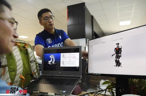 图为王昊老师（右）与王承业老师研究设计机器人的外形。新华网 姜冰摄